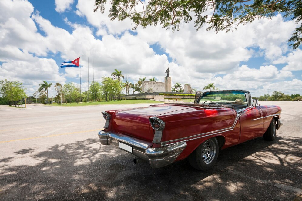 classic-convertible-car-with-monument-and-cuban-flag-in-background_23-2148226498